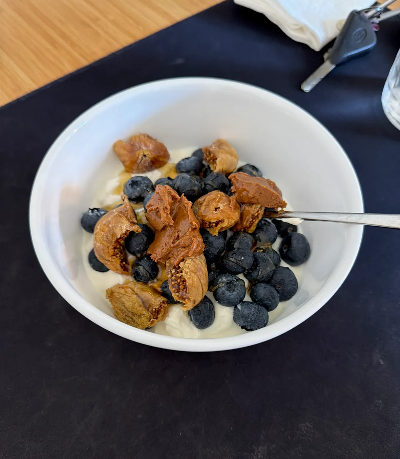 A Greek yoghurt breakfast bowl topped with almond butter, dried figs, blueberries and honey